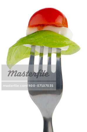 Caprese salad ingredients on the fork isolated on white.