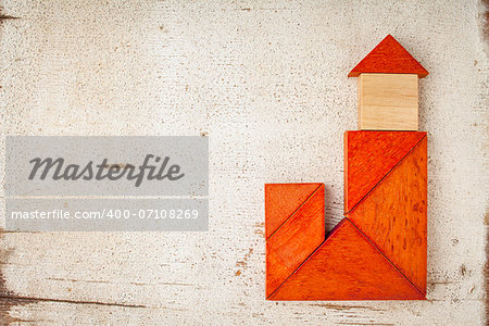 abstract house with a tower or church built from seven tangram wooden pieces, a traditional Chinese puzzle game; rough white painted barn wood background