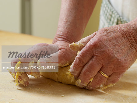 Close-up of elderly Italian woman's hands kneading pasta dough in kitchen, Ontario, Canada