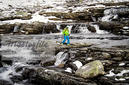 Man crosses mountain stream, water rushinng over rocks, Norway, Europe