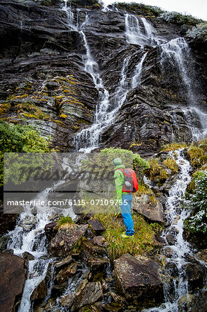 Hiker taking a look at waterfall, Norway, Europe