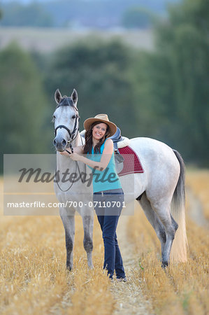 Young Woman Standing beside Quarab Horse in threshed Cornfield, Bavaria, Germany