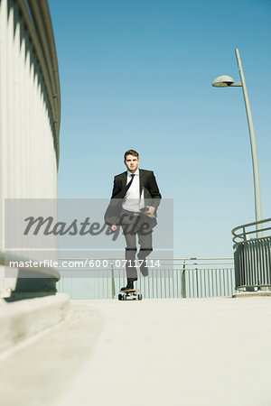 Businessman skateboarding on walkway holding binder, Germany