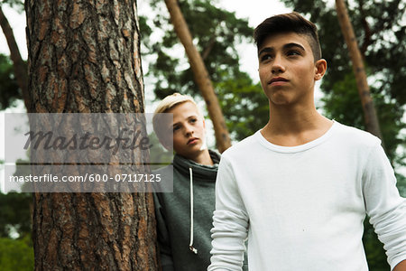 Portrait of two boys standing next to tree in park, Germany