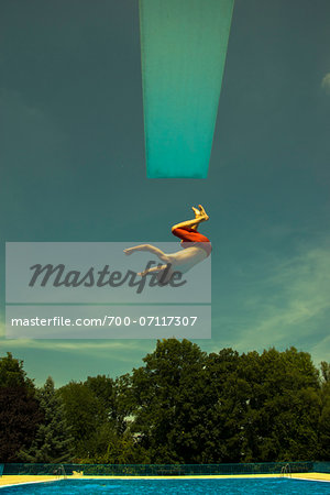 Teenage Boy Jumping into Swimming Pool from Diving Board, Langenbeutingen, Baden-Wurttemberg, Germany