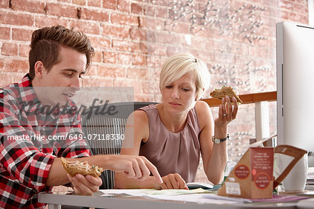Two colleagues eating sandwiches at desk