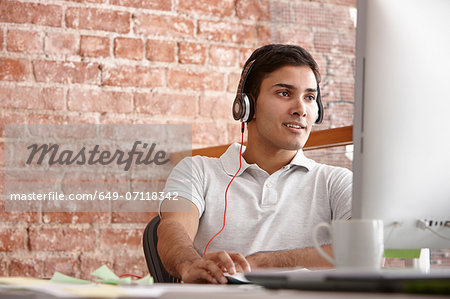 Young man using computer wearing headphones