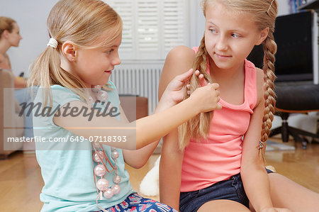 Girl plaiting sister's hair