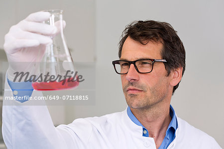 Male scientist examining ph-reaction of liquid in flask