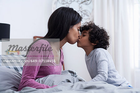 Son kissing mother in bed