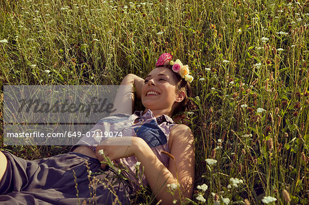 Young woman lying in meadow with flowers in her hair