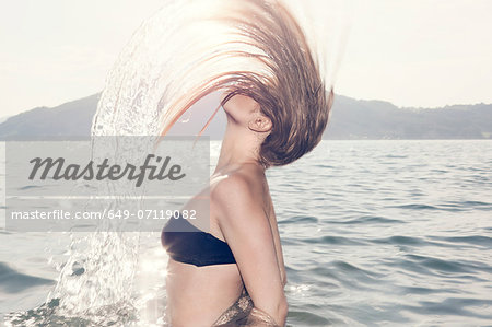 Young woman in sea throwing head back