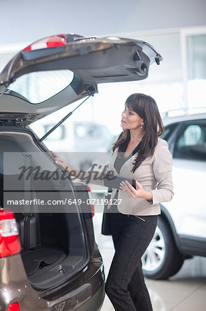 Mid adult woman checking car boot in showroom