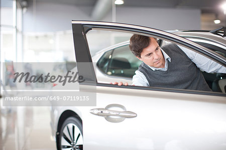 Mid adult man checking door in car showroom