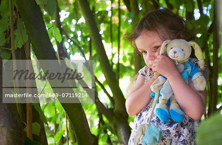 Portrait of female toddler with cuddly toy in woods