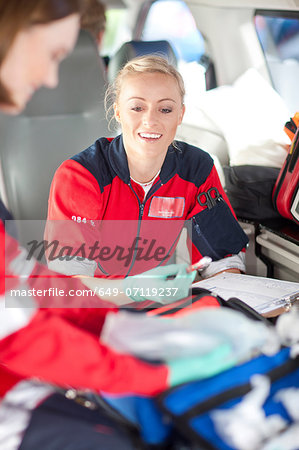 Two female paramedics in ambulance checking medical equipment