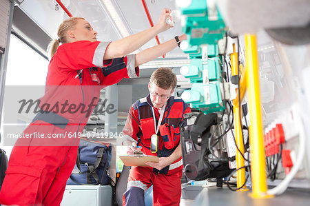 Paramedics in ambulance listing equipment