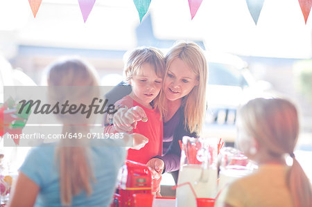 Two young sisters selling drink to brother and mother