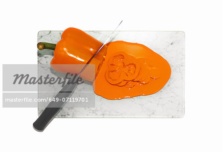 Kitchen knife cutting orange pepper
