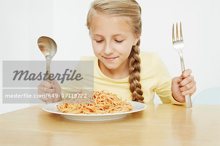 Girl with plate of spaghetti and oversized cutlery