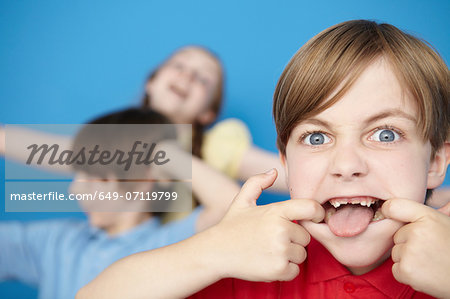 Portrait of boy sticking out tongue, blue background