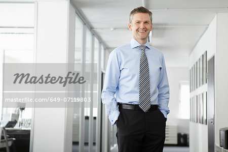 Portrait of mature businessman in office, hands in pockets