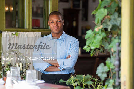 A Man Standing By The Open Window Of A Cafe Or Bistro, Looking Out With Arms Folded.