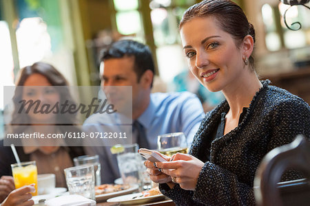 Business People. Three People Around A Cafe Table, One Woman Turning Around, Holding A Wine Glass.