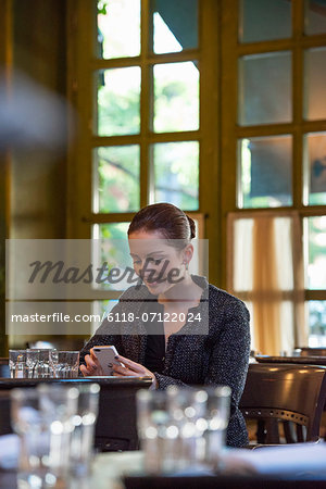 Business People. A Woman Sitting Alone At A Table. Checking Her Phone.