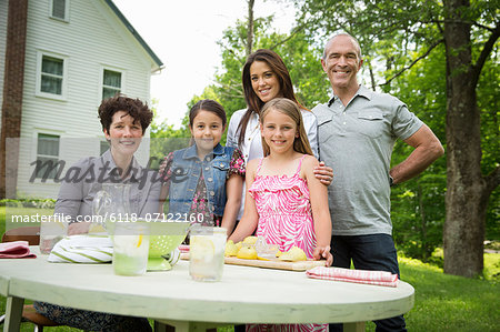 A Summer Family Gathering At A Farm. Five People Posing Beside The Table, Where A Child Is Making Fresh Lemonade.