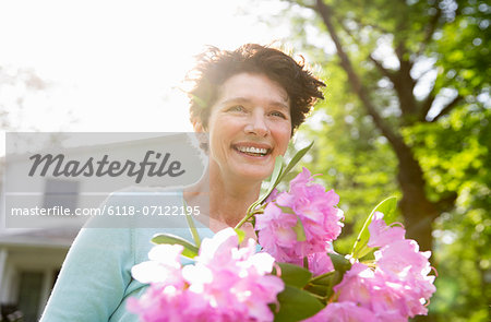 Family Party. A Woman Carrying A Large Bunch Of Rhododendron Flowers, Smiling Broadly. Family Party. A Woman Carrying A Large Bunch Of Rhododendron Flowers, Smiling Broadly.