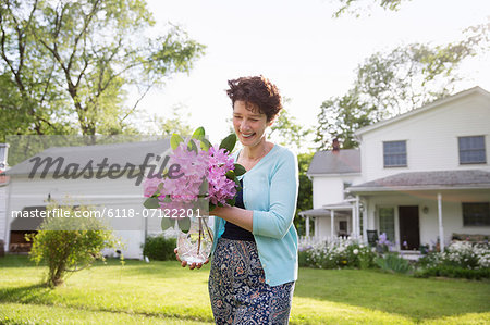 Family Party. A Woman Carrying A Large Bunch Of Rhododendron Flowers, Smiling Broadly.