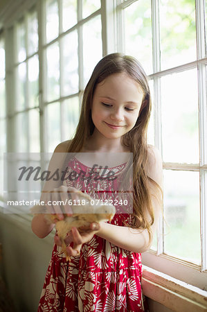 A Young Girl In A Floral Sundress, Holding A Young Chick Carefully In Her Hands. A Young Girl In A Floral Sundress, Holding A Young Chick Carefully In Her Hands.