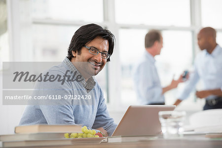 Office Life. A Young Man Sitting Using A Laptop Computer.