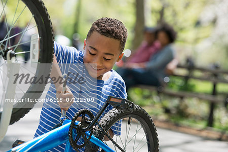 A Family In The Park On A Sunny Day. A Father And Son Repairing A Bicycle.