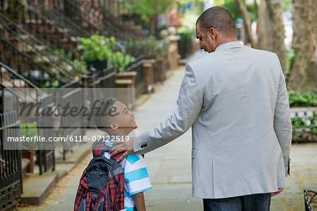 An Adult And A Child, A Father And Son, Walking Together On The Street In The City.