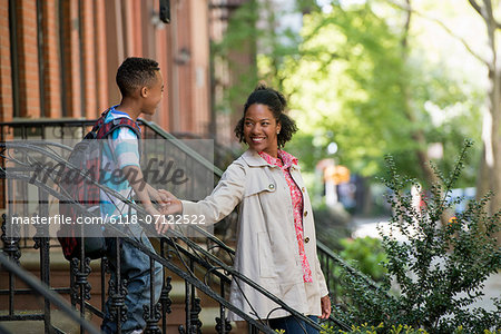 A Mother And Son, A Woman And A Boy On A Flight Of Steps Outside A Brownstone Building.