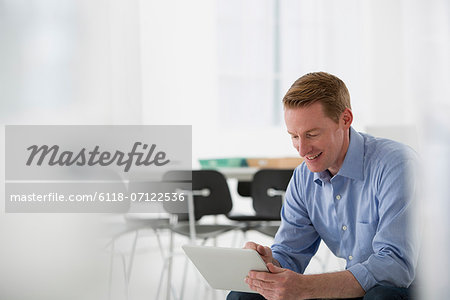 A Light Airy Office Environment. A Man Sitting Holding A Digital Tablet.