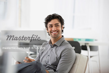 Business. A Man Seated Smiling And Holding A Digital Tablet.