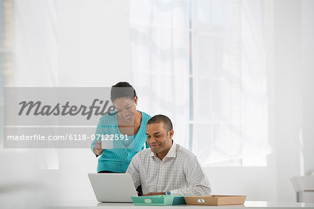 Business. A Woman With A Cup Of Coffee And A Man Looking At A Laptop.