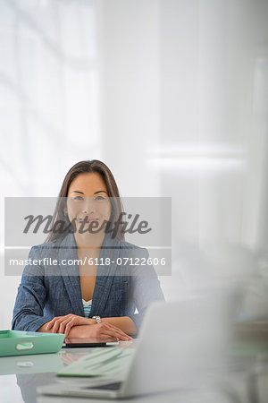 Business. A Woman Sitting At A Desk. Digital Tablet And Laptop, And Green Files.
