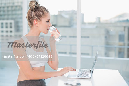Gorgeous athletic blonde in bright room drinking water