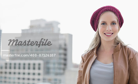 Smiling casual blonde posing outdoors on urban background