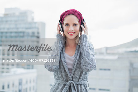 Cheerful pretty blonde listening to music outdoors on urban background