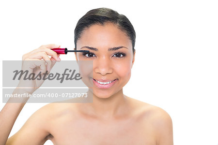 Happy young dark haired model applying mascara on white background