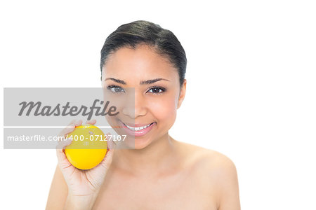 Seductive young dark haired model holding an orange on white background