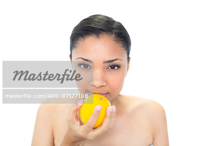 Calm young dark haired model smelling an orange on white background