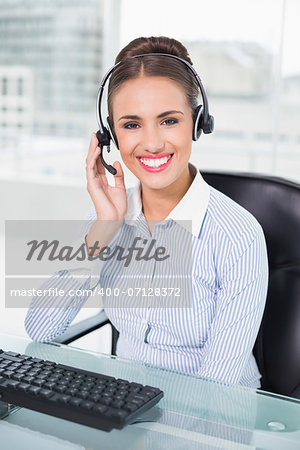 Cheerful businesswoman using headset in bright office