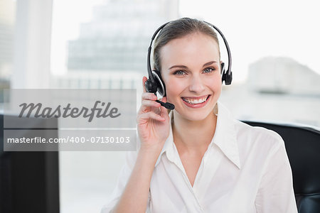 Happy call centre agent looking at camera in her office