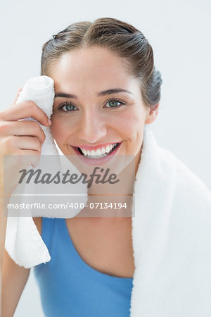 Close up portrait of a smiling young woman wiping sweat with towel